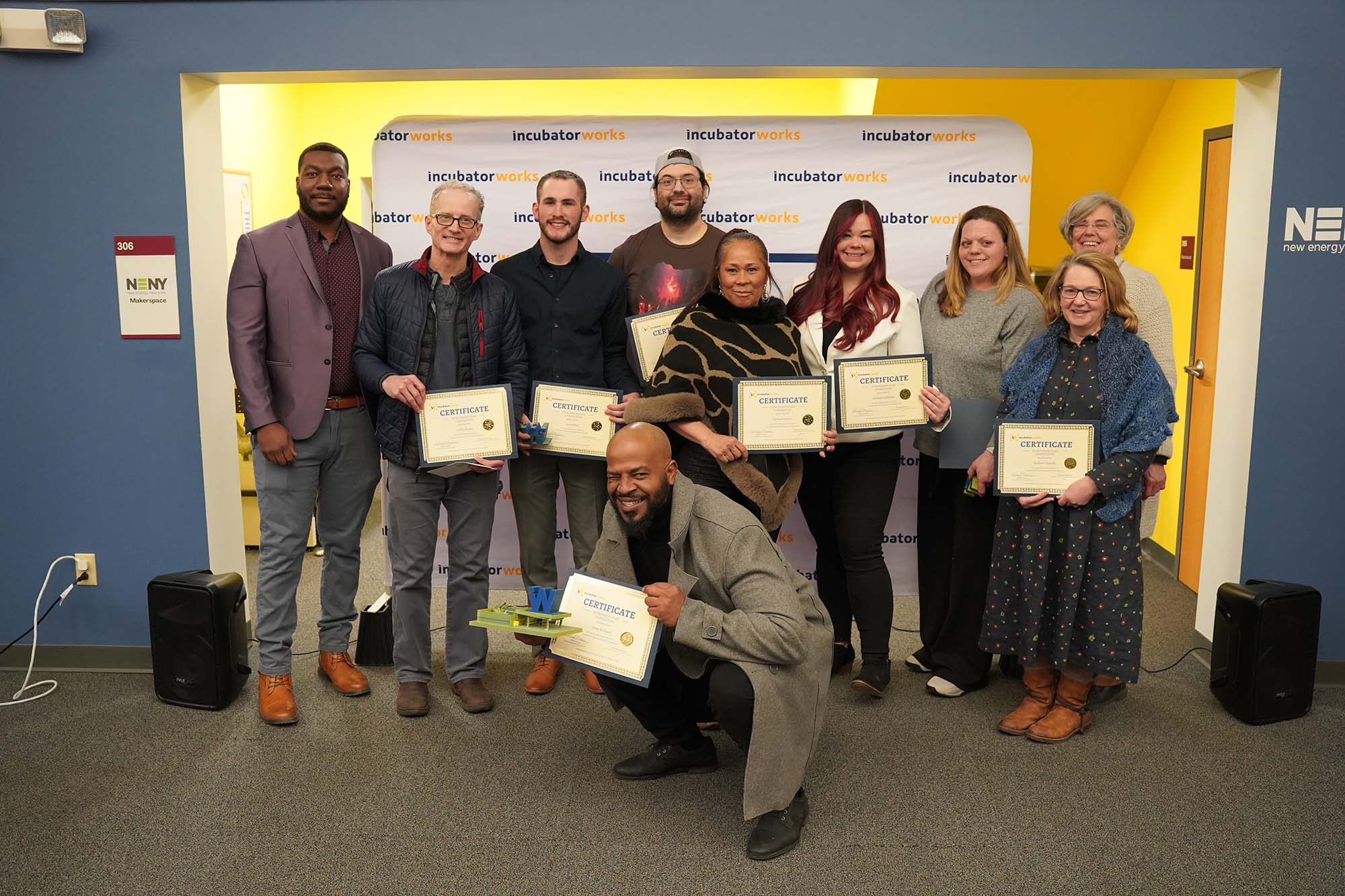 A group of graduates smiles with their Business Plan Completion certificates from IncubatorWorks